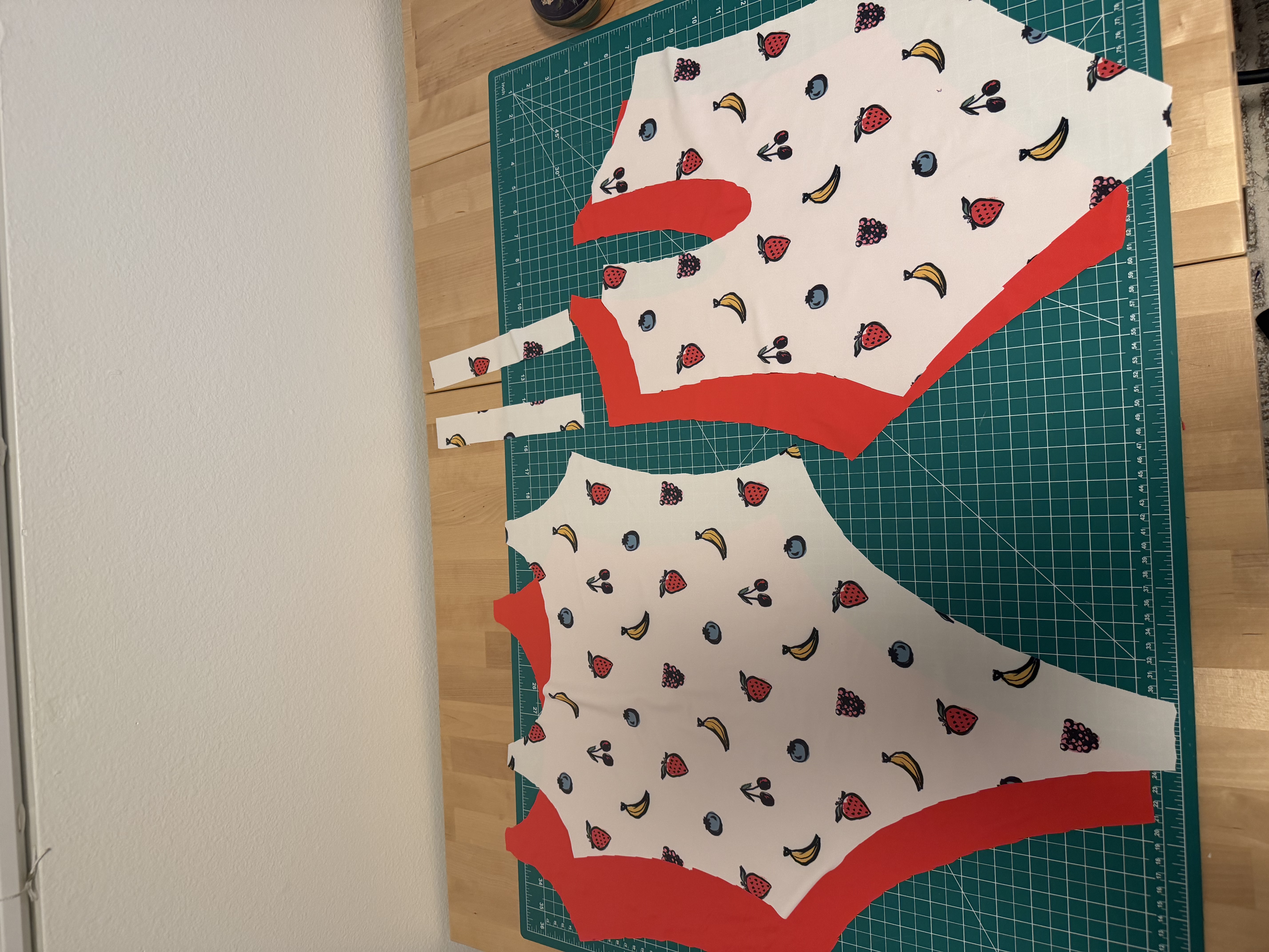 Cut pieces of the fruit print Olivia One Piece with the red lining fabric